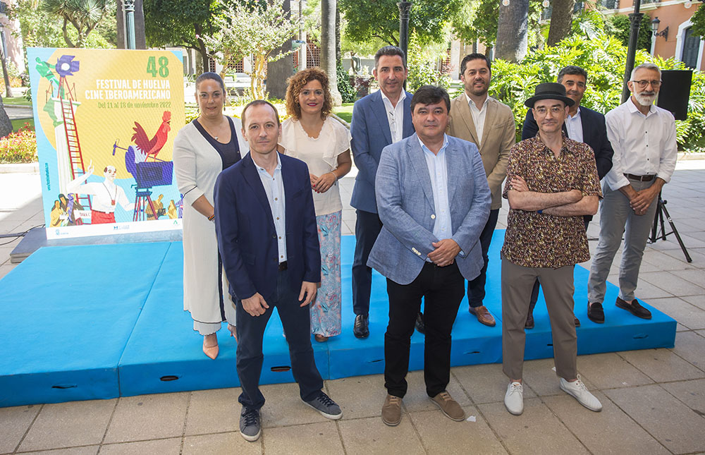 Foto de familia con el cartel de Huelva 2022. A la derecha, en la primera fila, el autor del mismo, José Luis Ágreda